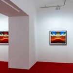 Una galleria d'arte con tappeto rosso e fotografie incorniciate appese al muro.