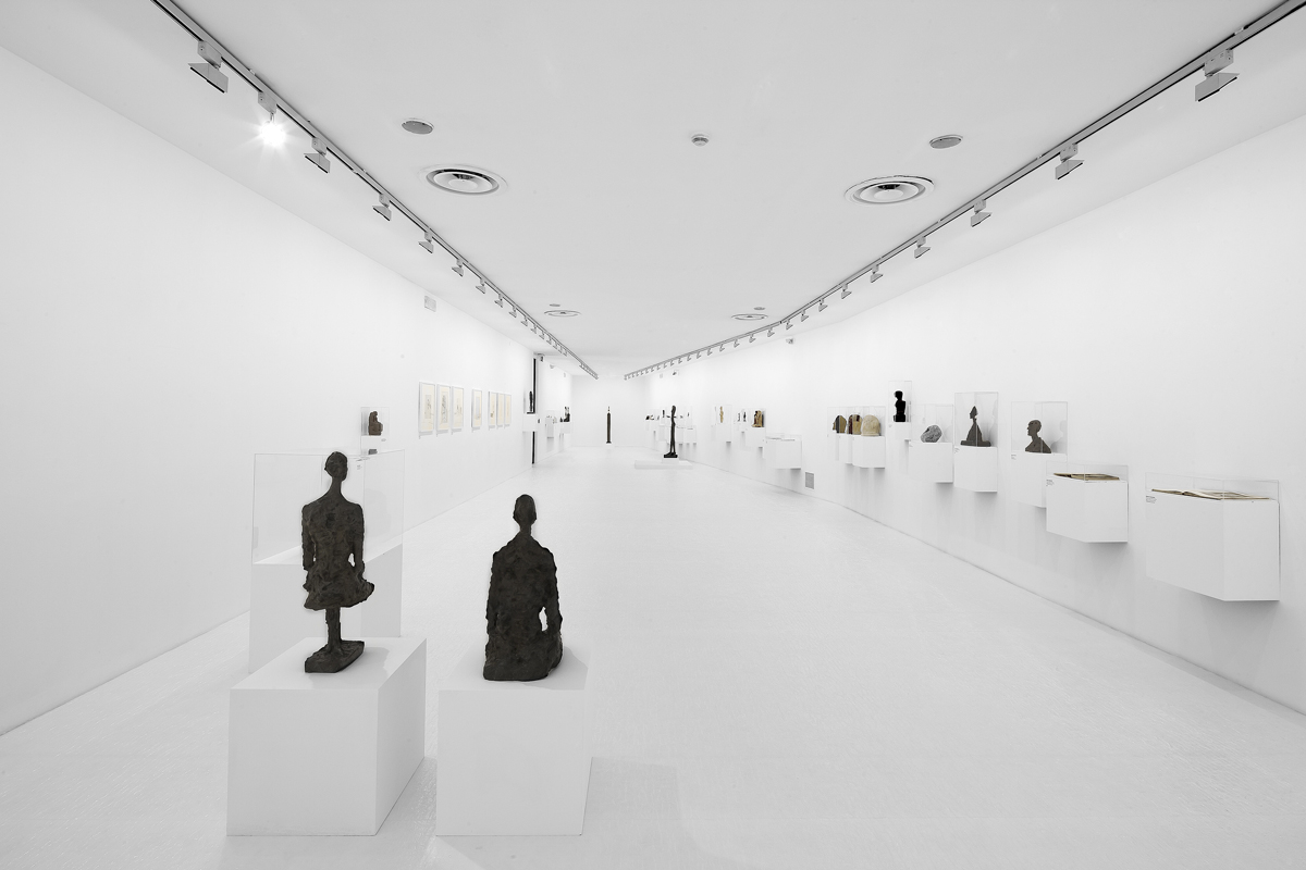 Vista di una galleria d'arte bianca con sculture su piedistalli.
